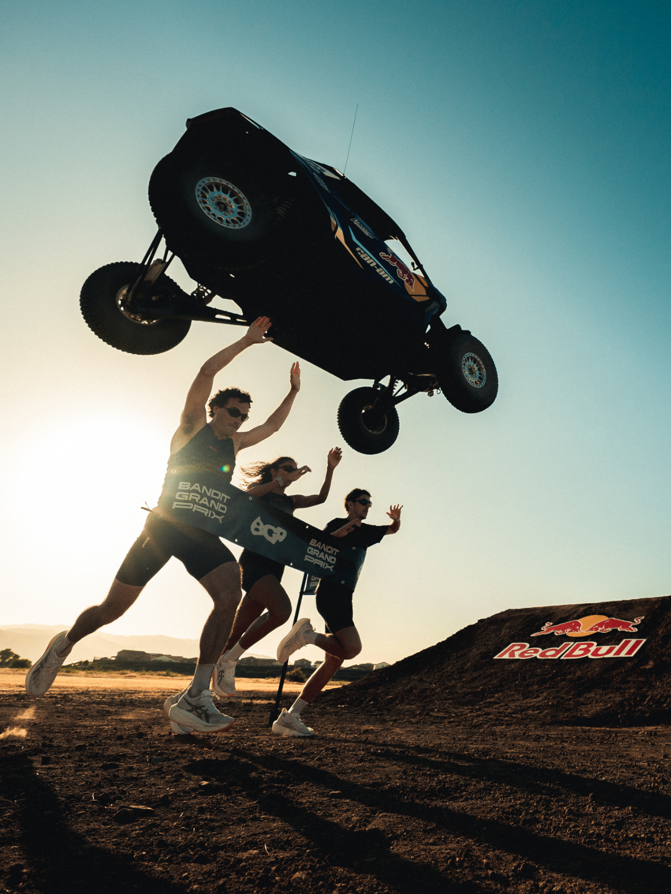 Runners breaking the Bandit Grand Prix tape as a Can-Am buggy launches overhead
