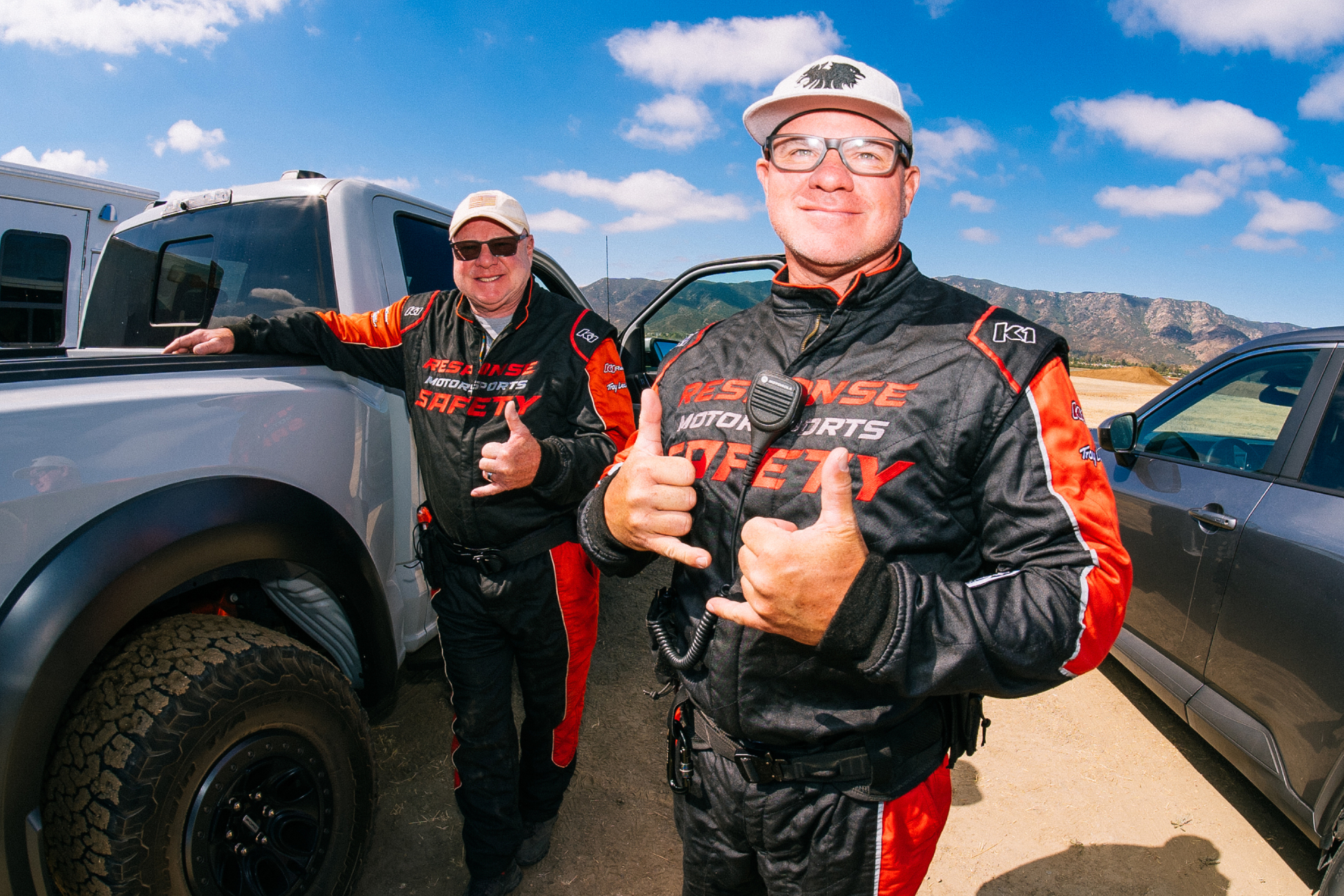Two Response Motorsports safety crew members giving thumbs up beside a truck and ambulance