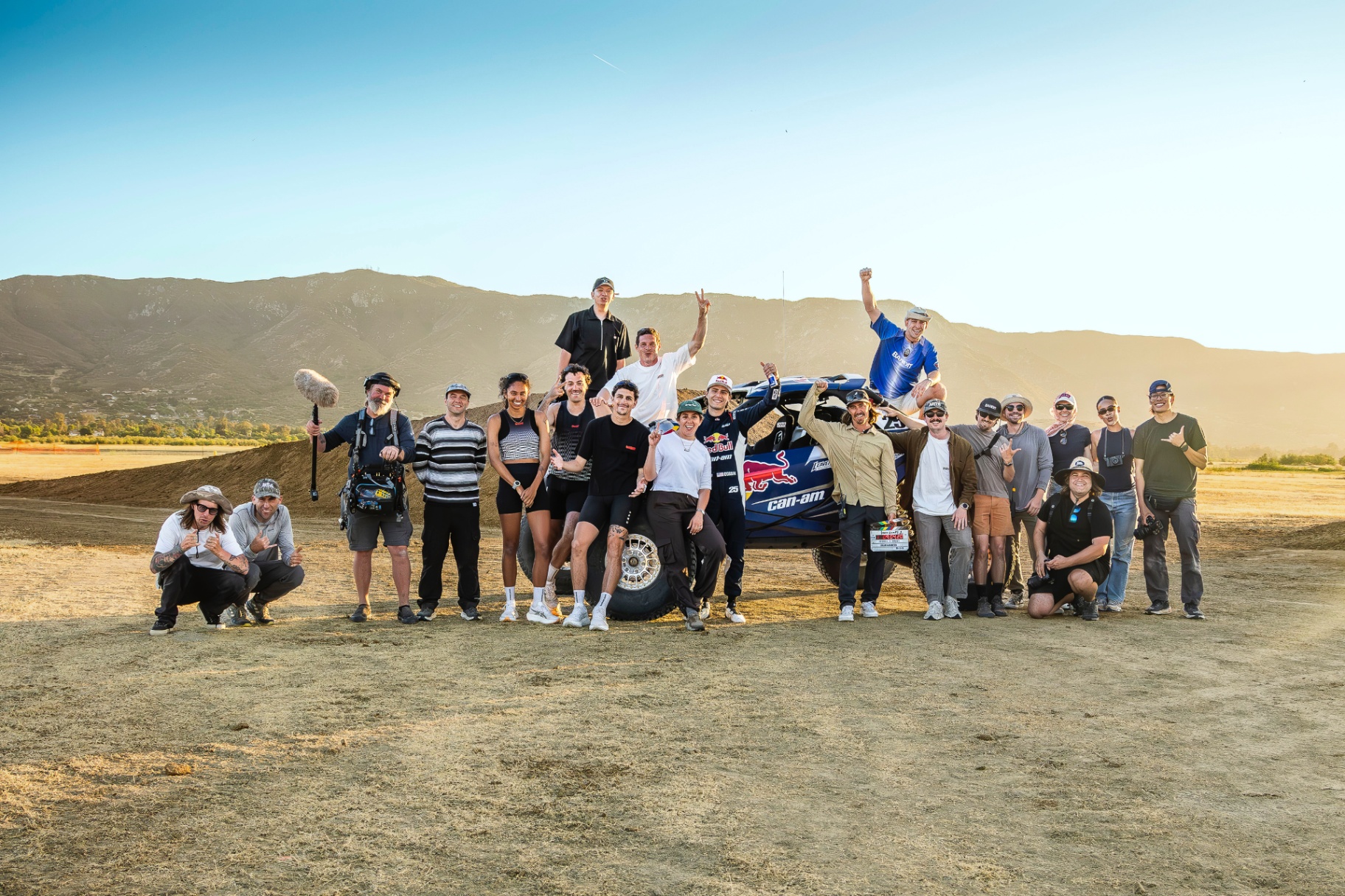 Bandit Grand Prix crew and runners posing with the Red Bull Can-Am buggy at golden hour in the desert